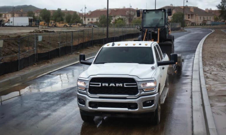 2022 Ram 2500 towing a bulldozer on a wet road