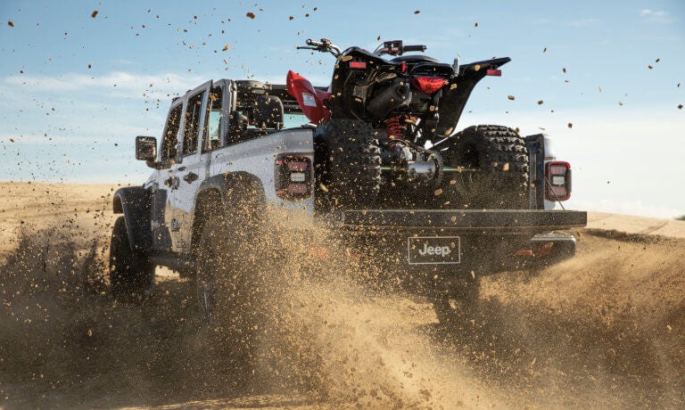 2025 Jeep Gladiator with ATV kicking up dirt