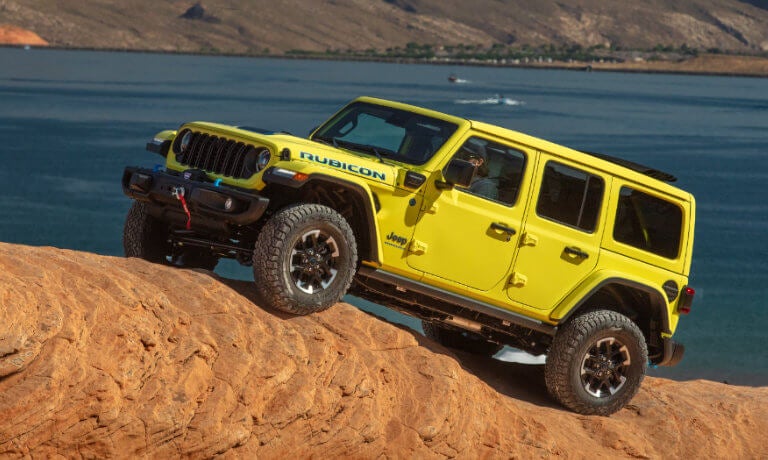 2025 Jeep Wrangler 4xe offroading on a boulder by a lake